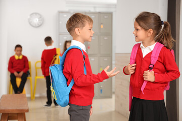 Fototapeta premium Little pupils with backpacks talking at school hall