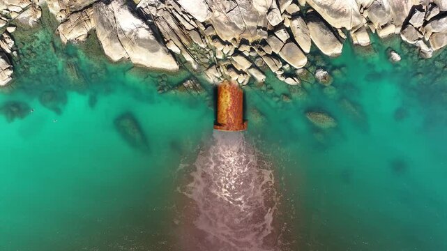 Stream of water flows out of the sewer pipe into the ocean. Pipeline of sewage discharged into sea, concept environmental impact. 