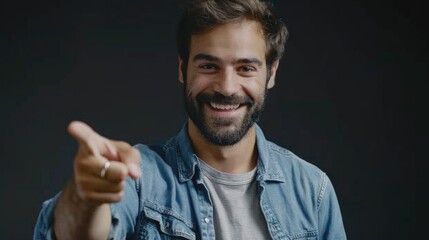 Obraz premium A person wearing a denim shirt points at the camera, suggesting attention or direction