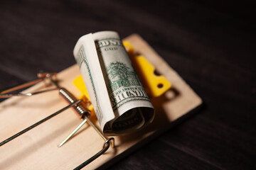 a lot of money in a mousetrap with a wooden background.