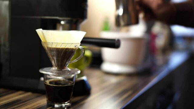 Man adding water to coffee dripping through pour over filter coffee maker. High quality 4k footage