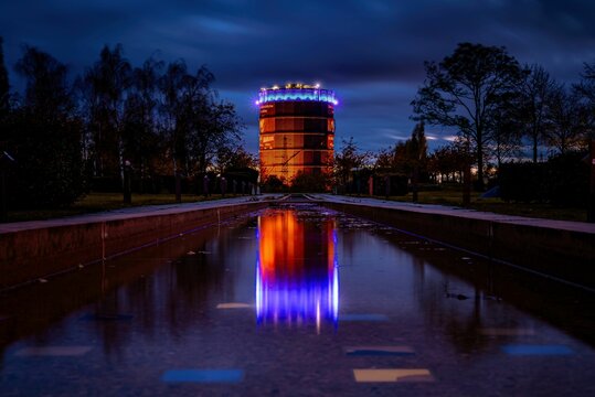 View of the Gasometer illuminated under a cloudy night sky in Oberhausen, Germany