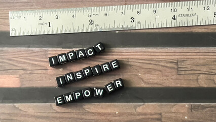 Concept of Impact Insipire Empower written on wooden blocks. Cross processed image on Wooden...