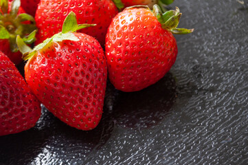 Fresh strawberries on black cover background with customizable space for text. Healthy food concept
