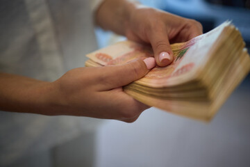 Obraz premium Woman with pink nails counts money, focused on cash, involved in finance and transactions