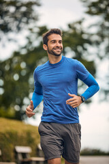 Fototapeta premium Morning, workout and man in park for running challenge, wellness and healthy outdoor exercise. Training, cardio and runner on path in nature with commitment, progress and athlete in muscle fitness.