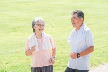 公園でウォーキング・有酸素運動する高齢者夫婦（シニア・男女）
