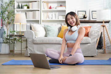 Obraz premium portrait young attractive asian girl in sportswear with headset and laptop prepare for exercise indoors in the living room