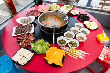 Tibetan hotpot or steamboat meal with various raw red meat and vegetable served on table in Sichuan...