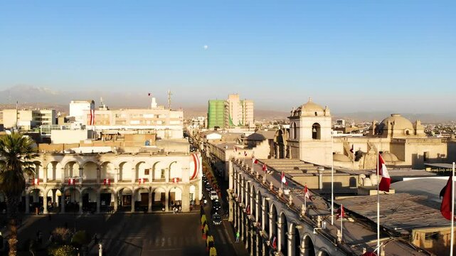 Portales de Arequipa en el mes patrio con banderas de peru en el atardecer, al fondo el volc&aacute;n Pichu Pichu y la luna 