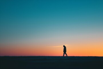 Fototapeta premium Silhouette of a person walking towards the right on the horizon, wide view, background solid 