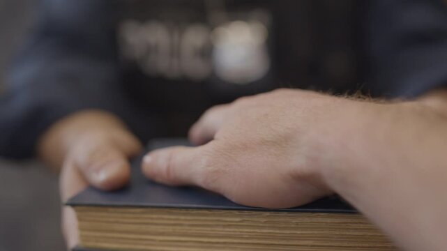 POV swearing on a bible in court room with police