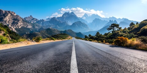 Naklejka premium Smooth asphalt road with majestic mountain peaks and clear blue sky