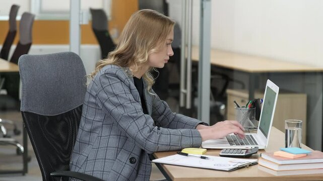 Corporate woman working in her desk, being problematic while using laptop. Side view of a woman making stress gesture for having mistake at work.