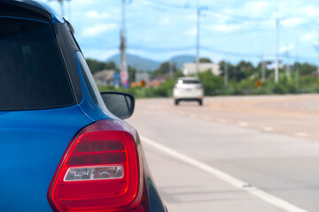 Rear side of car blue color parking beside of concrete road. Background of concrete path curves and traffic passes by.