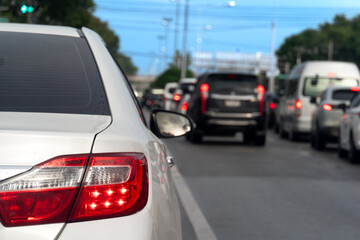 Fototapeta premium Luxury of white car stop on the asphalt road. Traveling in the provinces during the bright period. Open light brake. Many cars rushed forward in a long queue.