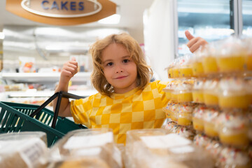 Kid choosing cakes, cupcake muffin. Kid on shopping in supermarket. Grocery store, choosing goods.