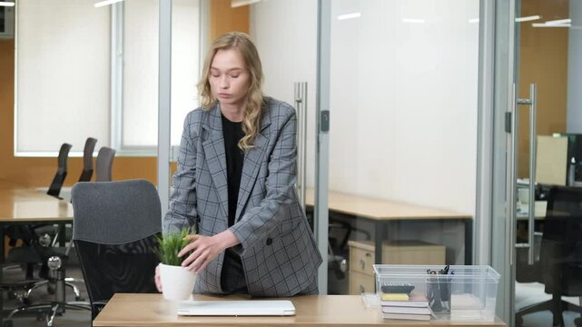 Businesswoman putting her personal stuff inside the plastic storage box. She clear the desk after work and put her laptop on the top of the box.