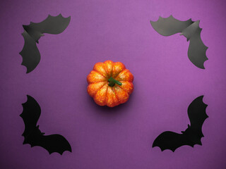 Fototapeta premium Halloween Pumpkin Decoration with Black Paper Bats on Purple Background