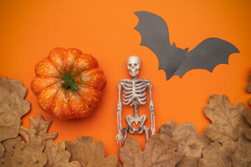Halloween Decorations: Pumpkin, Skeleton, Bat, and Autumn Leaves on Orange Background