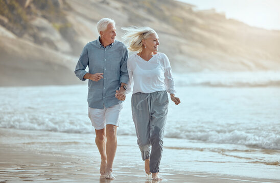Mature, couple and running on beach with love on retirement vacation, romance and together with fun or freedom. Man, woman and holding hands by ocean on holiday, happy and bonding with energy.