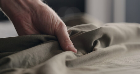 Fototapeta premium man touching taupe cotton clothes closeup