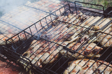 Spirals of spicy sausage grilling on a BBQ over hot flaming coals. Grilled natural spiral meat sausage