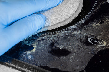 Person cleaning an electric hob with a scrubbing pad. Housework chore concept.