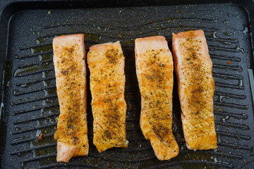 Grilled salmon fillets steaks with salt pepper and herb on grill.