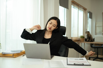 Young businesswoman stretching body at desk. Health and wellness in the workplace concept