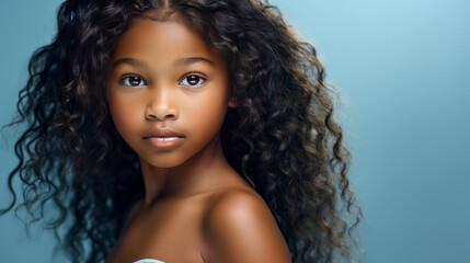 Fototapeta premium Portrait of smiling cute African American child girl with perfect skin, light blue background, banner.