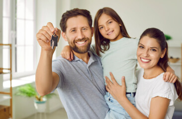 Portrait of a happy parents father, mother with child girl on moving day smiling with a key of a...