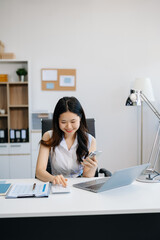 Asian businesswoman working in the office with working notepad, tablet and laptop