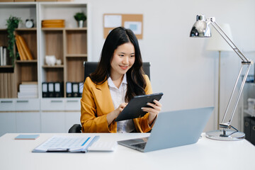 Asian businesswoman working in the office with working notepad, tablet and laptop