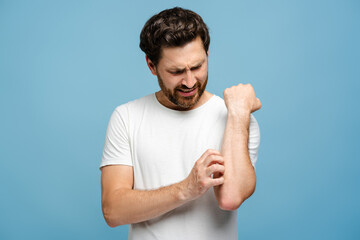 Young man with allergy on the hand suffering from virus, posing over blue background