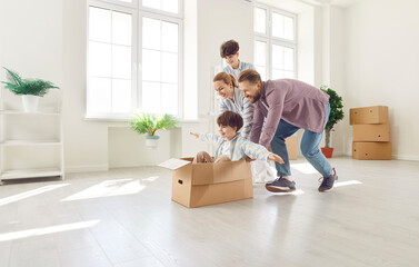 Happy family with children, parents and two sons, celebrating relocation or moving to a new home or real estate. Riding the youngest son in a box, symbolizing happiness for the new chapter in lives.