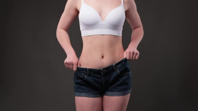 girl in short denim shorts. The girl stretches the skin on the leg, showing fat deposits. Treatment and getting rid of excess weight, the deposition of subcutaneous fat.