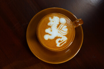 cafe latte with unicorn latte art, served on brown porcelain cup, in a cafe environment