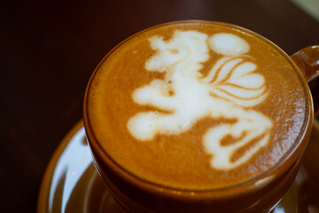 cafe latte with unicorn latte art, served on brown porcelain cup, in a cafe environment