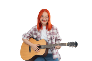 A girl with red hair is sitting on a chair and holding a guitar. She is smiling and she is enjoying herself. Isolated on white background.