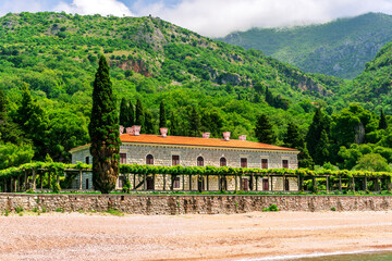 Naklejka premium beautiful summer season landscape of scenic coast with beach and nice architecture building of hotel or palace with awesome green garden and great mountains on background