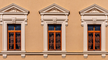 Fototapeta premium facade architecture wall with three beautiful vintage windows in old european style on warm yellow background