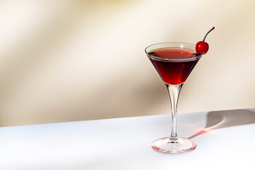Manhattan alcoholic cocktail drink with whiskey, red vermouth and cherry in martini glass. Beige background