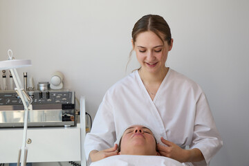 Fototapeta premium Young female cosmetologist preparing for facial treatment with client