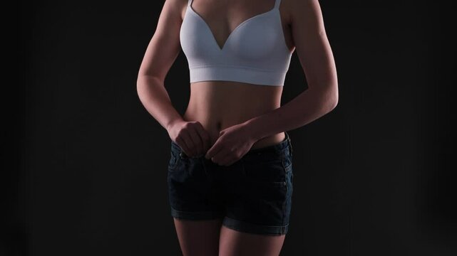 girl in short denim shorts. The girl stretches the skin on the leg, showing fat deposits. Treatment and getting rid of excess weight, the deposition of subcutaneous fat.