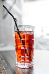 strawberry coctail on wooden table in street cafe, red coctail with mint, ice and straw