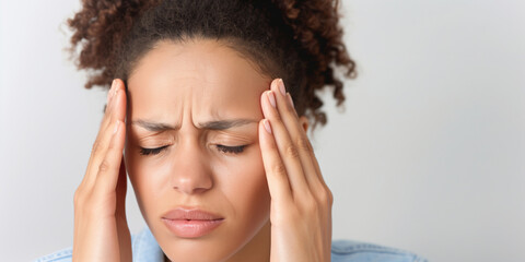 Fototapeta premium Woman with curly hair experiencing headache while holding her temples, banner