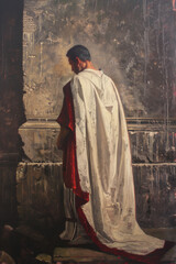 Naklejka premium Roman Pontius Pilate wearing a traditional toga stands contemplatively by a stone wall in dim light. Historical reenactments, classical studies, Roman history, traditional clothing.