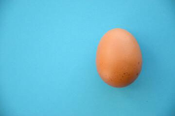 Uncooked egg on pastel blue background. Minimal food concept with copy space