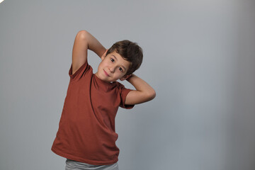 A young boy is smiling in a casual outfit against a gray backdrop, looking carefree and cheerful